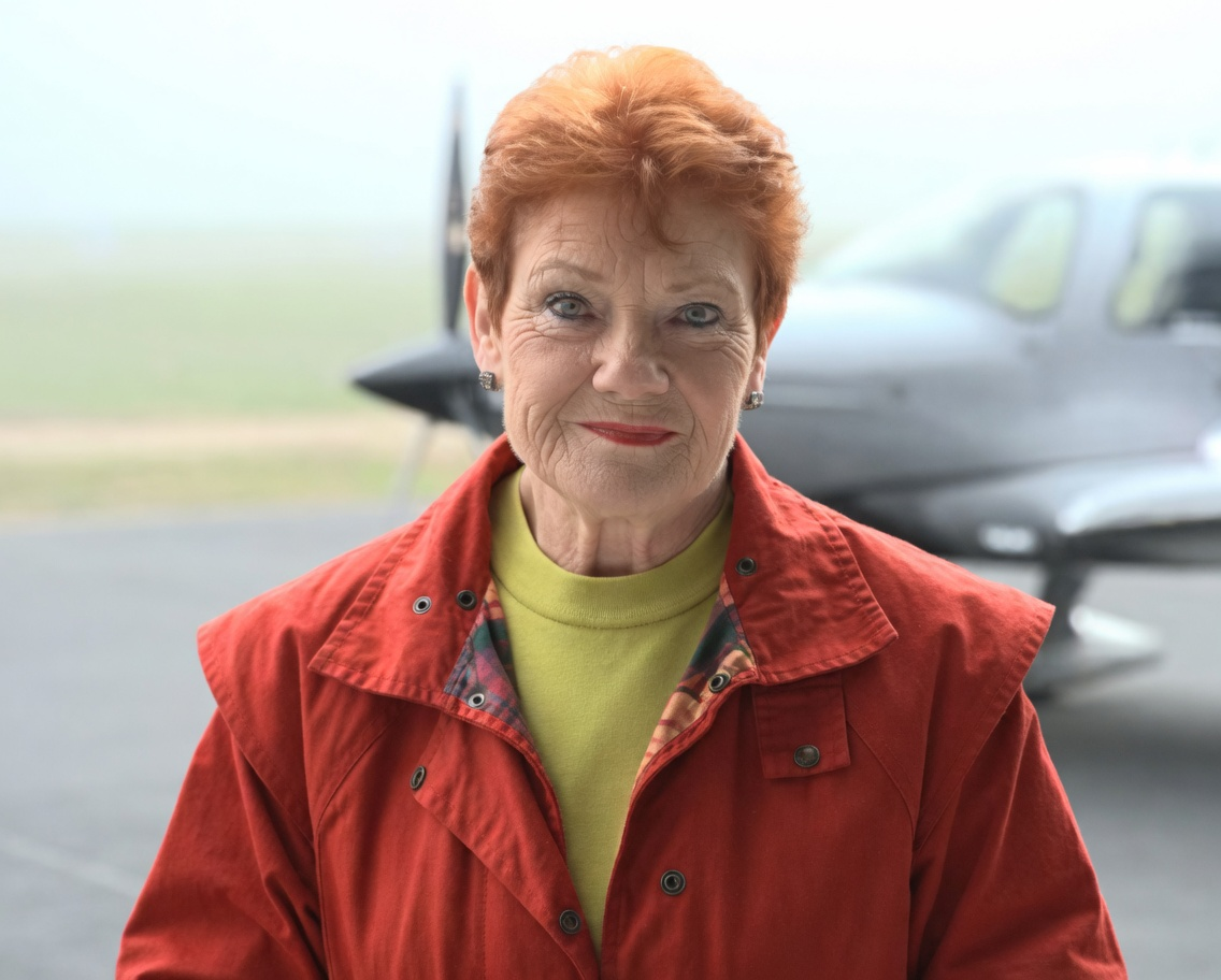 Pauline Hanson standing confidently in front of a small aircraft