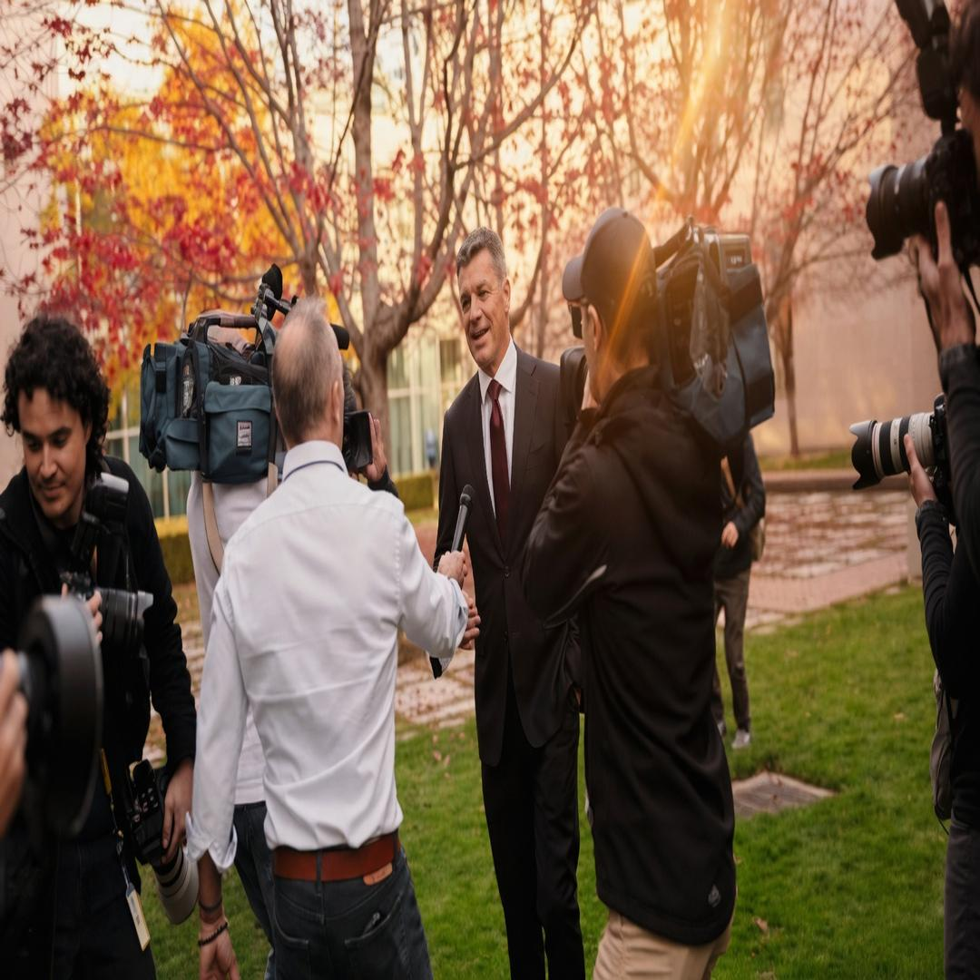 Angus Taylor speaking to a scrum of television reporters and camera crews on a lawn