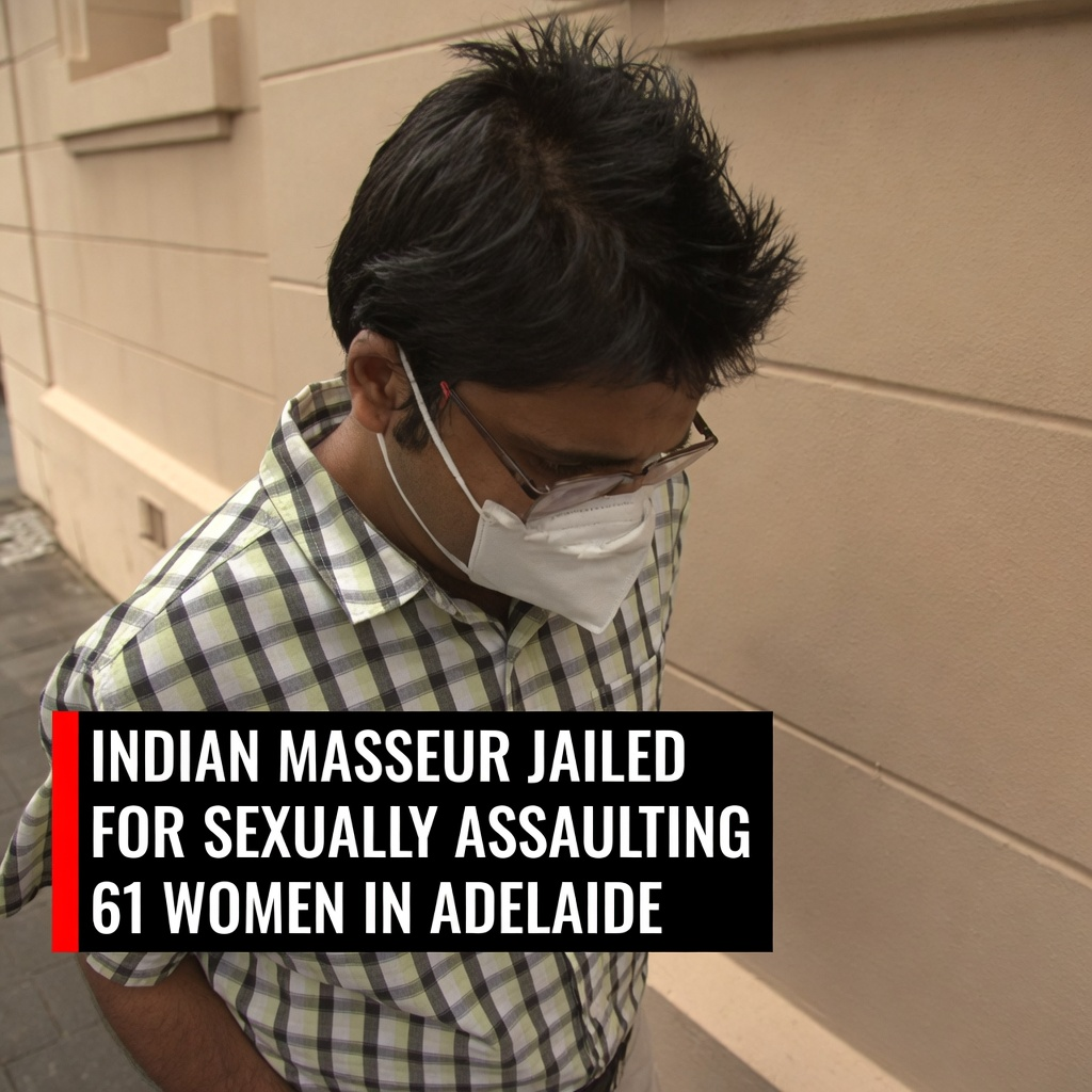 Sumit Satish Rastogi in a plaid shirt and face mask walking past a light beige wall