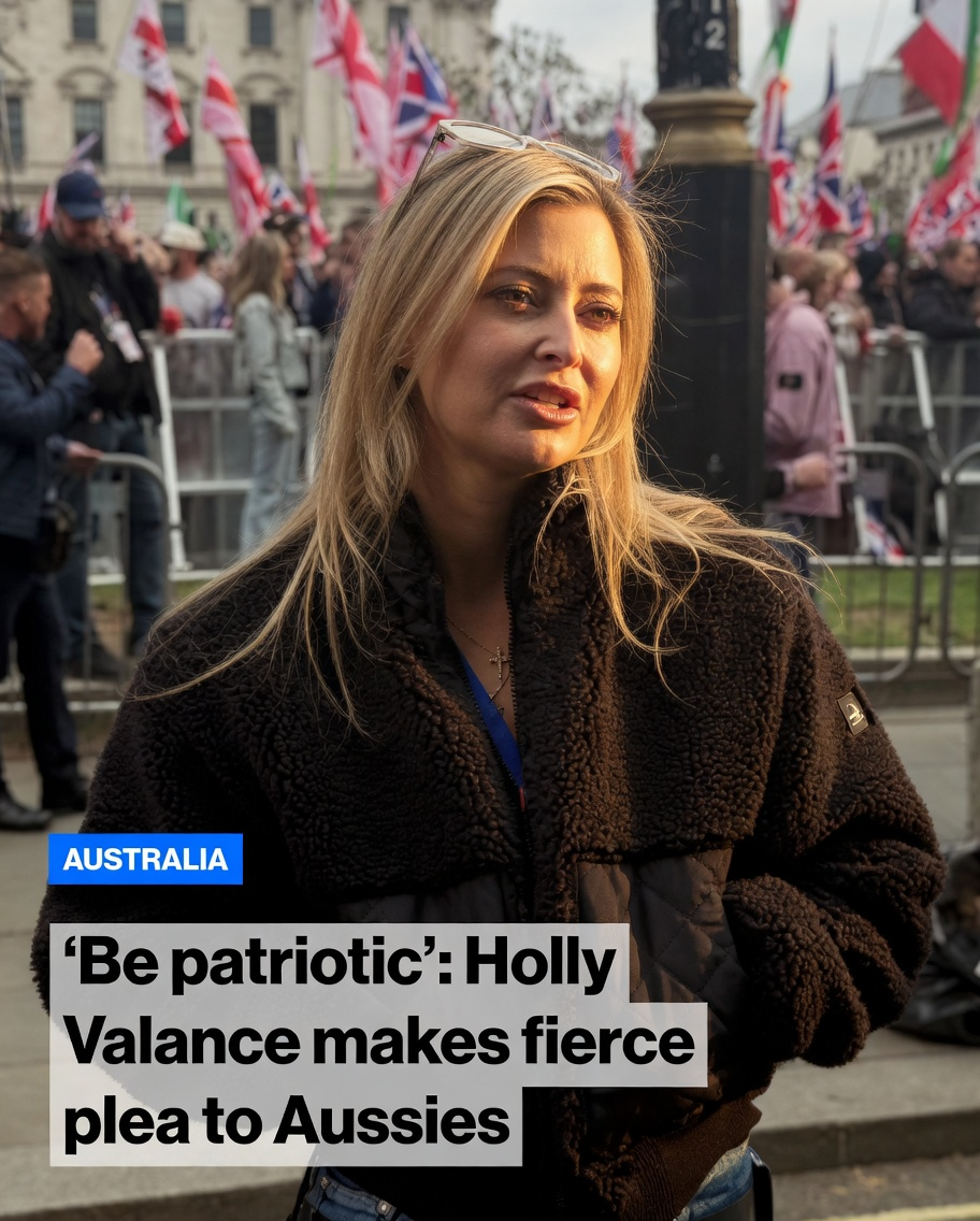 Holly Valance in a brown sherpa jacket standing before a crowd holding Union Jack flags