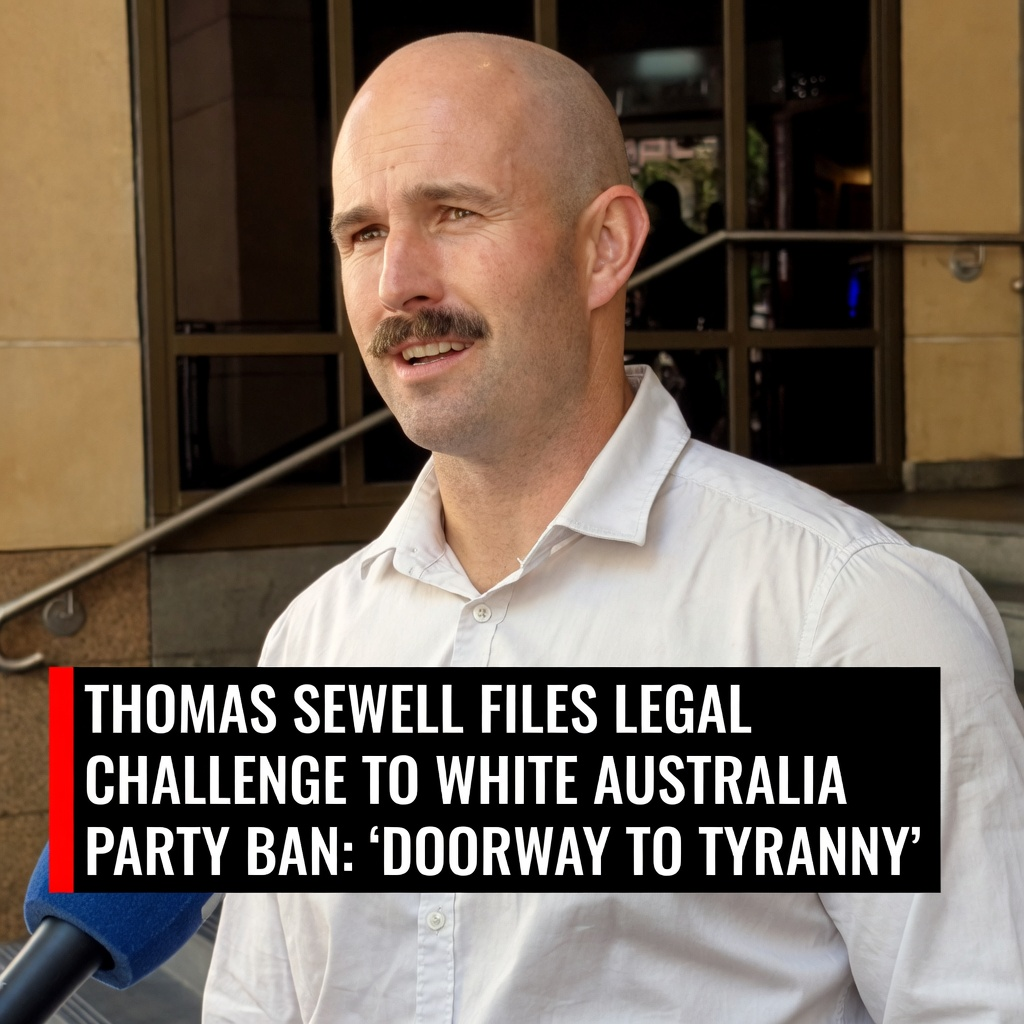 Thomas Sewell in a white dress shirt during a media brief next to a bold doorway to tyranny headline