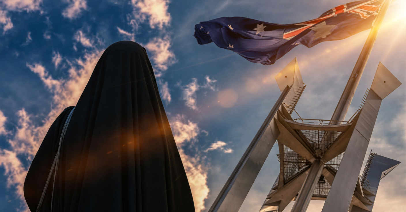 Rear view of a woman in a black burqa looking at the Australian flag flying above parliament