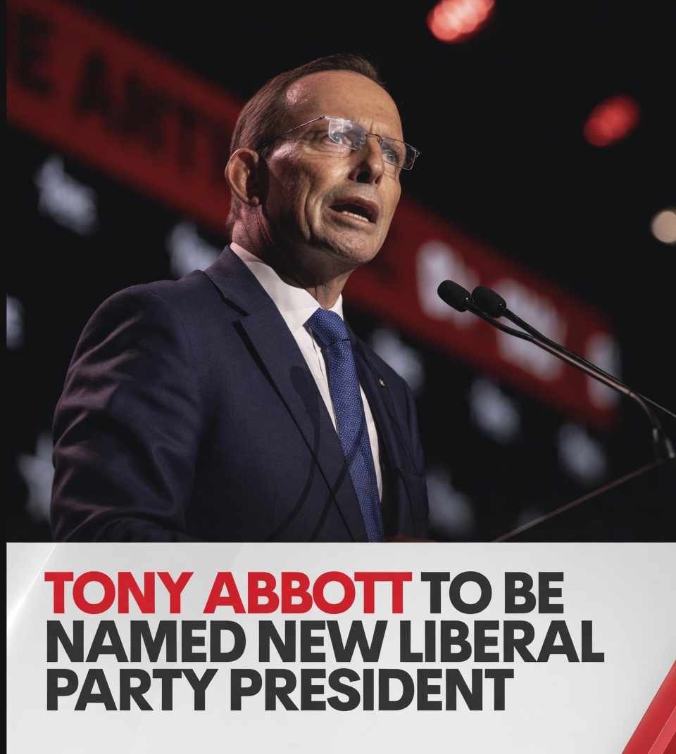 Tony Abbott in navy blue suit jacket and spectacles speaking behind twin microphones inside an auditorium
